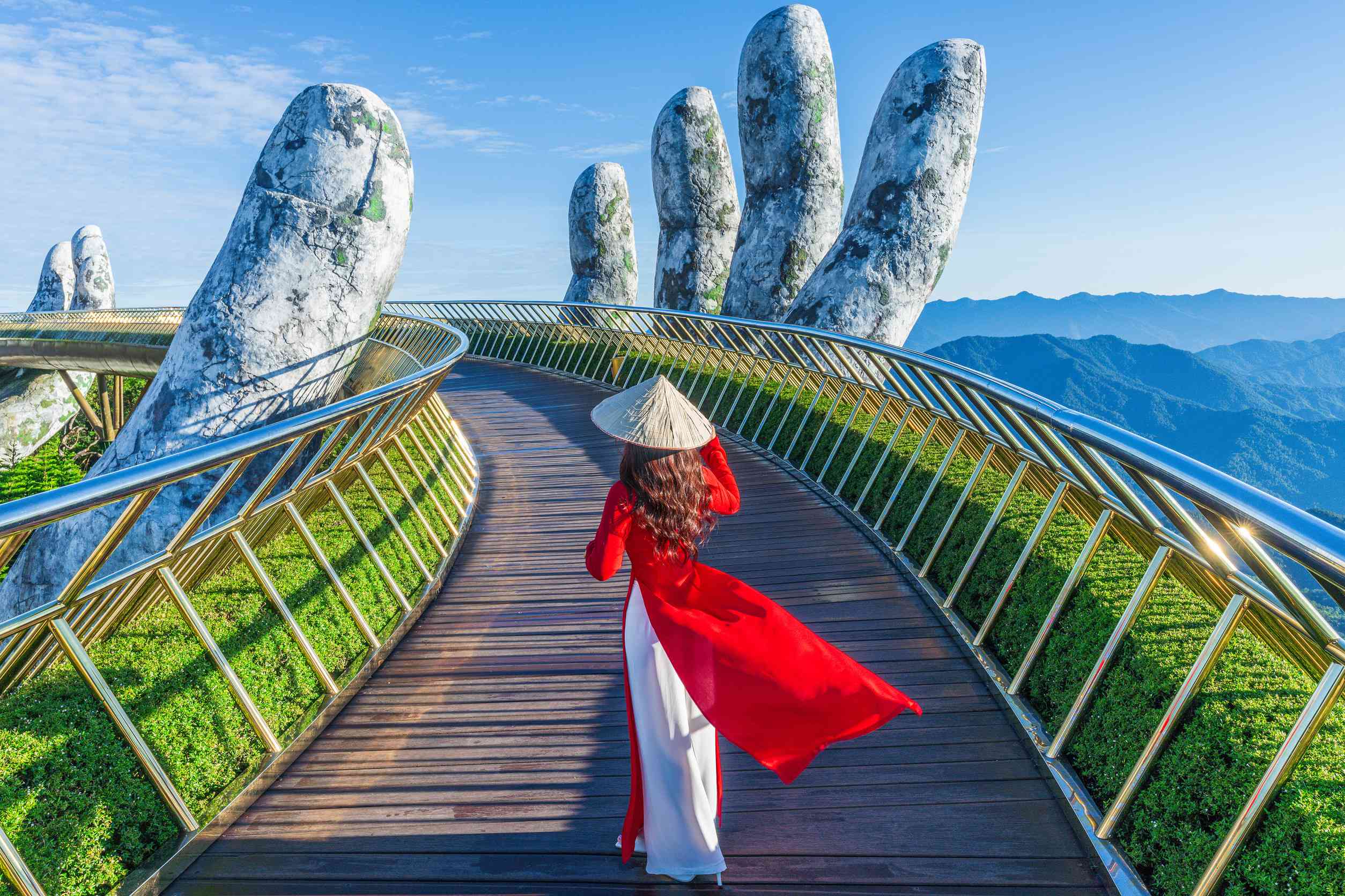 Asian female tourist walks on golden bridge in Ba Na Hills, Danang, Vietnam