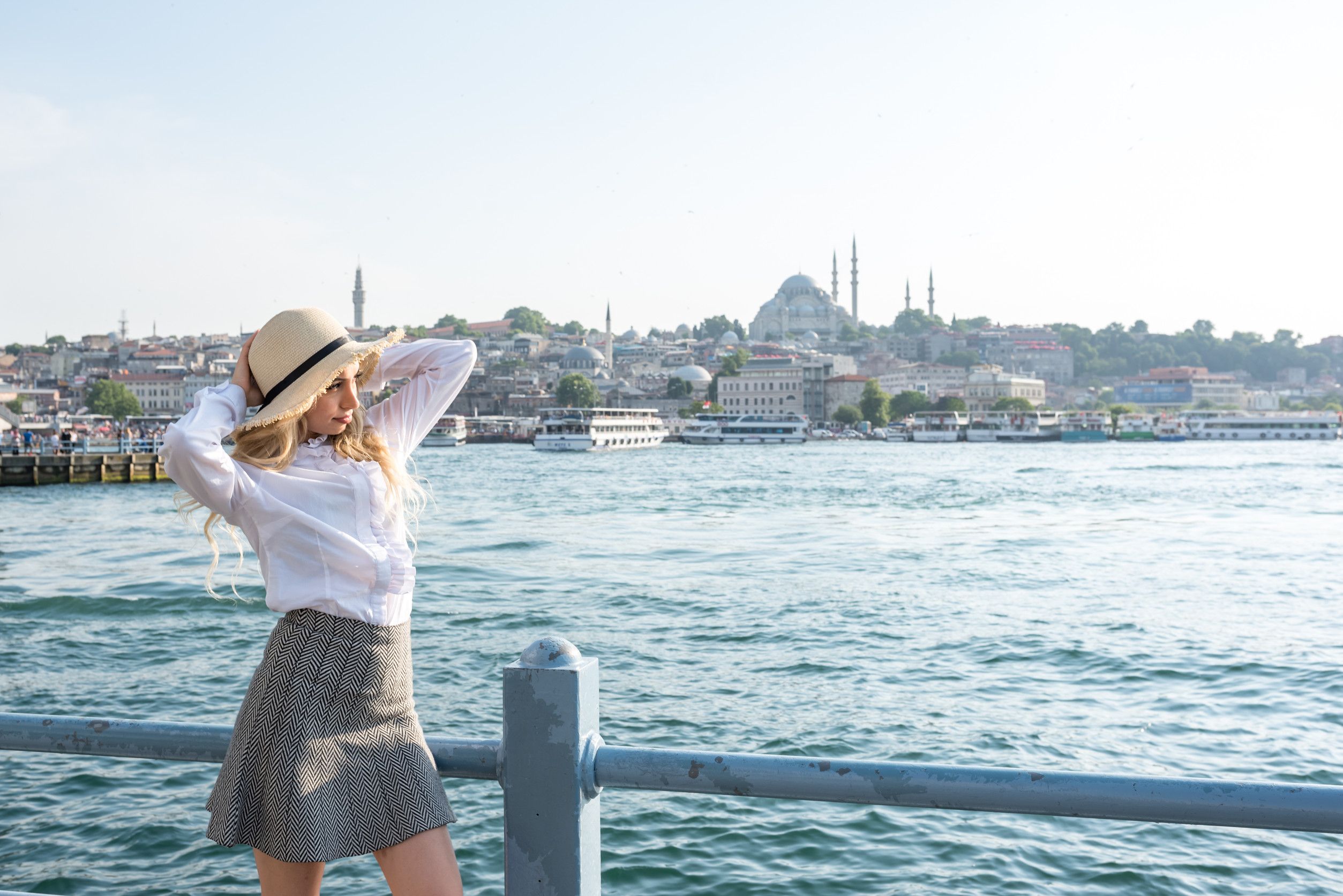 Attractive young beautiful girl stands over Galata bridge and enjoys view of Bosphorus in Istanbul